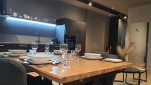 A modern dining area with a wooden table set for four, equipped with plates, bowls, glasses, and cutlery.