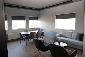 Relax in this spacious living area with a dining table, sofa, and coffee table, offering a view of the outside.