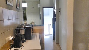A narrow kitchen with a stove, a coffee maker, and a sink. - Check Point - Museum (Athens)