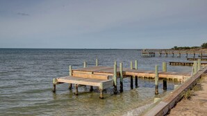 A wooden pier extending into calm waters with a clear sky.