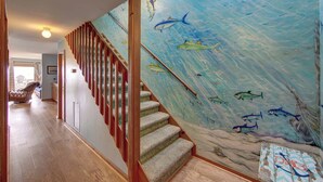 A staircase with a wooden handrail and a mural of fish on the wall.