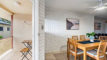 A dining area with a brick wall, wooden table, and chairs.