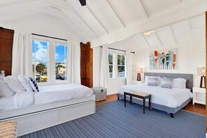 Quarto com duas camas, janelas amplas, vista exterior e uma pintura na parede.