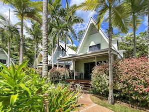 A resort with multiple bungalow-style buildings, surrounded by lush greenery and palm trees.