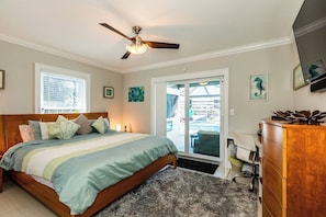 A bedroom with a bed, a ceiling fan, a dresser, and a view of a pool through a sliding glass door.