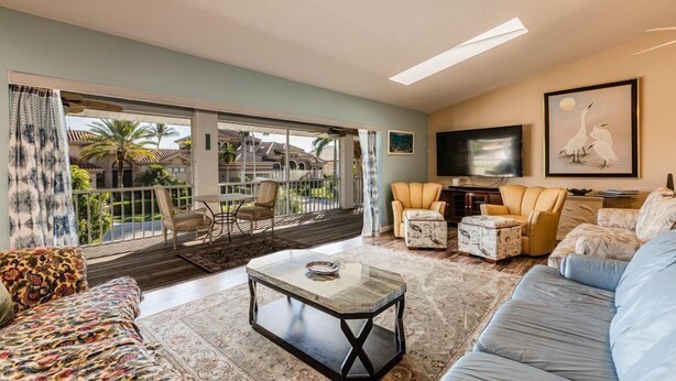 A spacious living room with a large window, a flat-screen TV, and a comfortable seating area.