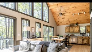 Un amplio salón con un sofá grande de color gris, techo de madera y vistas al exterior.
