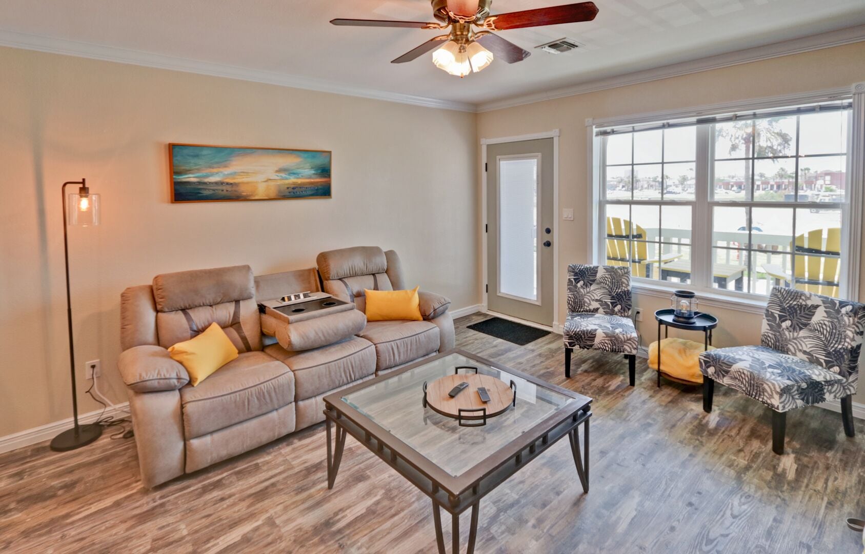 A living room with a sectional sofa, two armchairs, a coffee table, and a ceiling fan.