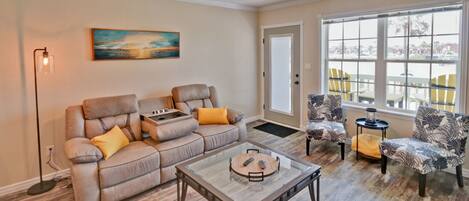 A living room with a sectional sofa, two armchairs, a coffee table, and a ceiling fan.