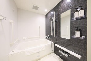 A modern bathroom with a bathtub, shower, and built-in vanity with soap dispensers. - Hotel Sui Akasaka by Abest (Tokyo)