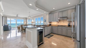 A spacious kitchen with a large island, grey cabinets, and a stainless steel refrigerator. - Adagio A-205 - Amazing UPDATED Gulf Front Corner Unit! (Santa Rosa Beach)