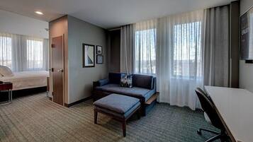 Ein Hotelzimmer mit Bett, Sofa, Schreibtisch und Stuhl.