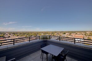 A balcony with a table and chairs, offering a view of a cityscape.
