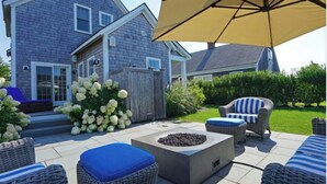 A patio area with wicker furniture, a fire pit, and a large umbrella. - Mid island oasis! 3-bedroom, 4 bath in the middle of “second downtown” (Nantucket)