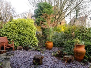 Un jardin avec un banc, des plantes en pot et un chemin pavé de pierres.