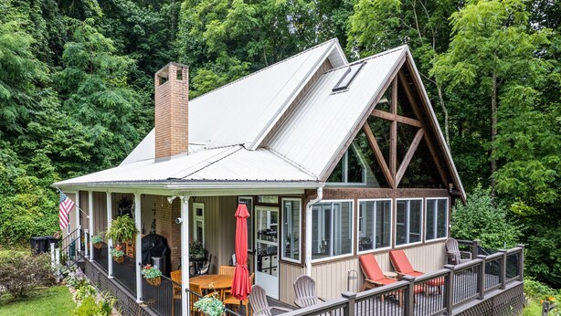 A house with a covered porch, a chimney, and a deck with outdoor seating. - Halfback Ridge -Hot Tub-Magnificent Views-Motorcycle & Pet-Friendly-Fenced Yard
 (Maggie Valley)