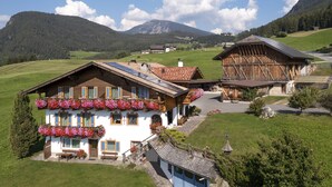 A traditional chalet with a sloped roof, wooden exterior, and flower boxes on the balcony. - Binterhof vacation apartment GENZIANA (Trentino-Alto Adige)