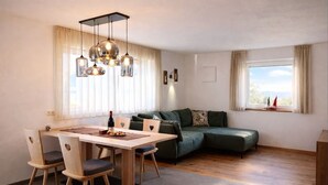 A modern living room with a dining area, a green sofa, and a large window with curtains. - Binterhof vacation apartment GENZIANA (Trentino-Alto Adige)