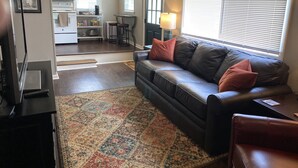 A living room with a leather sofa, a coffee table, and a patterned rug. - The Carriage House in SoMa (Little Rock)