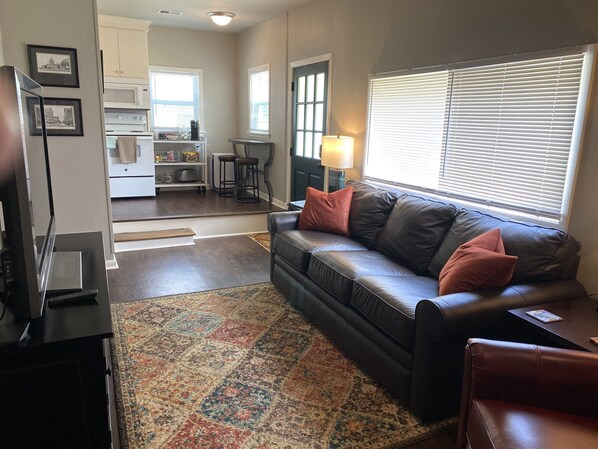 A living room with a leather sofa, a coffee table, and a patterned rug. - The Carriage House in SoMa (Little Rock)