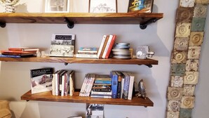 Three wooden shelves with books, a camera, and decorative items. - The Carriage House in SoMa (Little Rock)