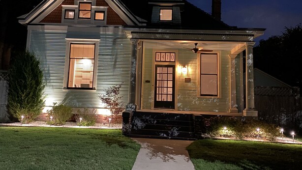 A two-story house with a front porch, a visible number '1410' on the door, and a chimney on the roof. - The Carriage House in SoMa (Little Rock)