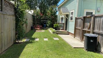 A backyard with a wooden fence, a small patio, and a house.