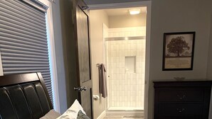 A bedroom with a bed, a door leading to a bathroom, and a dresser. - The Carriage House in SoMa (Little Rock)