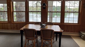 Ein Essbereich mit Tisch und vier Stühlen, große Fenster mit Seeblick und einer Wandlampe.