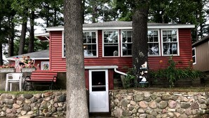 Ein rotes Haus mit einer Steinmauer, einer Haustür und einer Veranda mit einer Bank.