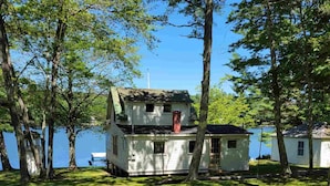 A two-story cabin with a chimney, surrounded by trees and a lake. - "Uptacamp" feel, true Maine style Camp (Lincolnville)