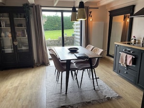 A dining area with a table, chairs, and a rug. There is a kitchen area with cabinets and a stove. - Charming and stylish vacation homes (Tardinghen)