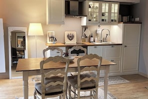 A compact kitchen with a dining table, chairs, a coffee maker, and cabinets.
