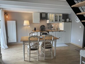 A compact kitchen with white cabinets, a wooden dining table, and two chairs.