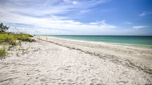 Una playa arenosa con cielo despejado y mar tranquilo.