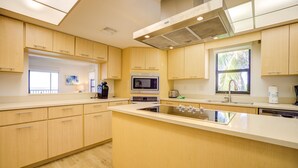 Una cocina moderna con armarios de madera, una isla central, un microondas y un ventanal grande.