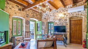 Un intérieur rustique avec des murs en pierre, des meubles en bois, un lustre et un téléviseur.