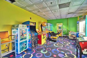 A brightly colored arcade room with various gaming machines and a patterned carpet. - Beachfront Escape to Unwind & Take in the Ocean Air (Myrtle Beach)