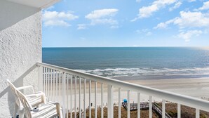 Uma varanda com vista para o oceano e a praia.