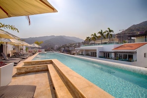 A swimming pool with lounge chairs and a view of a hillside town.