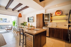 A modern kitchen with a central island, wooden cabinets, and a large window providing a view of the outdoors.