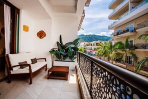 Ein Balkon mit einer Couch, einem Holztisch und einem Topfpflanzen.