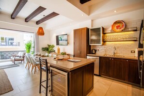 A modern kitchen with a central island, wooden cabinets, and a large window overlooking a balcony.