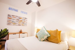 A bedroom with a bed, pillows, a nightstand, a wall art piece, and a ceiling fan. - Pool, 2 Balconies, Romantic Zone, Walk Everywhere (Puerto Vallarta)