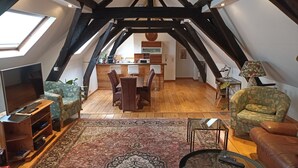 Un loft acogedor con comedor, sala de estar con televisor y asientos, y una cocina al fondo.