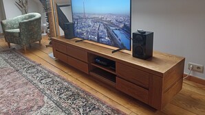 Una sala de estar moderna con un televisor de pantalla plana grande, un mueble de entretenimiento de madera y una alfombra estampada.