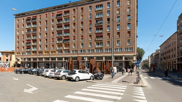 Ein mehrstöckiges Hotel mit einer Reihe geparkter Autos davor.