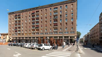 Een hotel met meerdere verdiepingen en een rij geparkeerde auto's ervoor.
