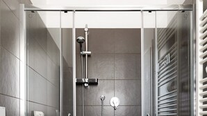 Ein modernes Badezimmer mit einer Duschkabine aus Glas, einer weißen Toilette und einem fest installierten Handtuchhalter.