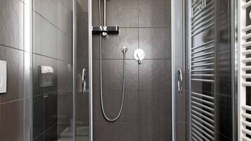 Een moderne badkamer met een douchecabine van glas, een wit toilet en een ingebouwde handdoekhouder.